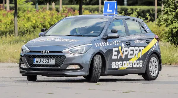 Szara Skoda z literą L na dachu, oznakowana jako "Szkoła Jazdy EXPERT". Pytanie o prawo jazdy od ilu lat jest tu na miejscu, bo to auto do nauki jazdy.