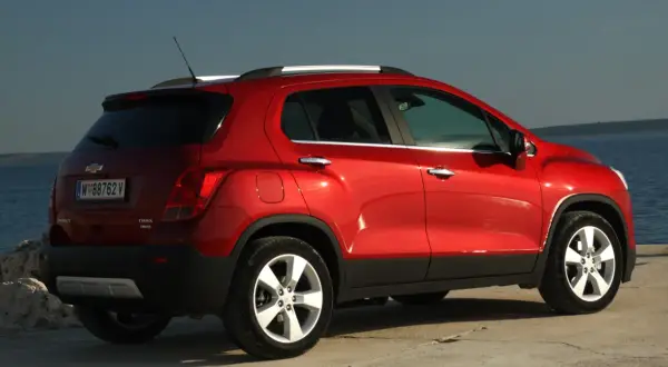 Czerwony Chevrolet Trax z tablicą rejestracyjną W 88762 V stoi nad morzem.