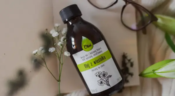 Butelka z naturalnym, nierafinowanym olejem z wiesiołka, idealnym do pielęgnacji włosów. Delikatne kwiaty podkreślają jego naturalne pochodzenie.