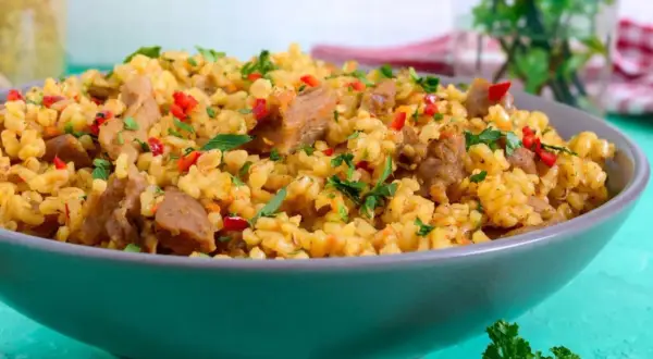 Pyszne kaszotto z kurczakiem, papryką i natką pietruszki, podane w szarej misce.
