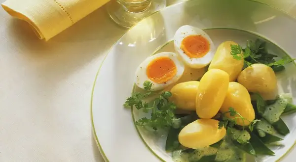 Ein einfaches zuckerschoten rezept: Salzkartoffeln, hartgekochte Eier und Zuckerschoten mit Kräutersauce auf einem Teller.