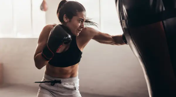 Focused female boxer practices double end bag drills, her punches a blur of motion.