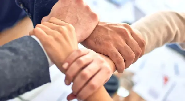 Dłonie splecione w geście współpracy, symbolizujące siłę networkingu i wspólnego celu.