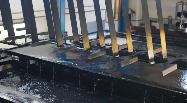 Parti metalliche immerse in un bagno per il trattamento fosfatante, pronte per la verniciatura.