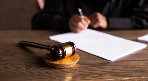 Młotek sędziowski na drewnianym stole, obok dokumenty. Sądowa decyzja o nieważności postępowania kpc zapadnie wkrótce.