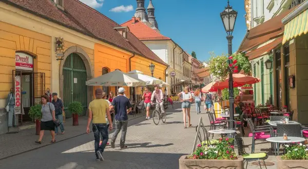 Tętniąca życiem ulica w Egerze, Węgry. Ludzie spacerują, jeżdżą na rowerze, siedzą w kawiarniach. Węgry atrakcje turystyczne.