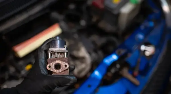 Zardzewiały zawór EGR w dłoni mechanika. Zastanawiasz się egr co to? To kluczowy element układu recyrkulacji spalin.