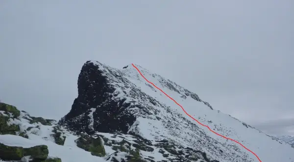 Snöklädda bergstoppar med en röd markerad led som leder uppåt. En utmanande sylarna topptur i vinterlandskap.