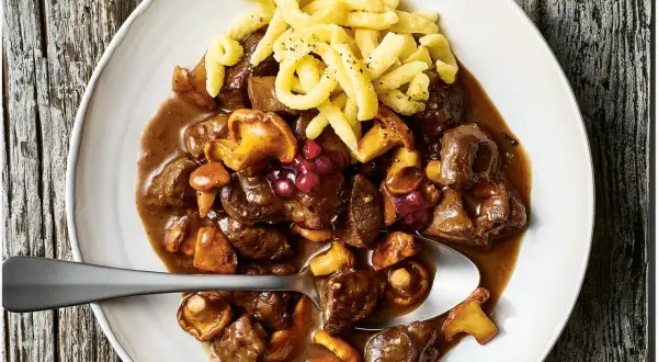 Herzhaftes Rehgulasch mit Rotwein, Pilzen und Preiselbeeren, serviert mit Spätzle. Ein köstliches Rehgulasch Rezept.