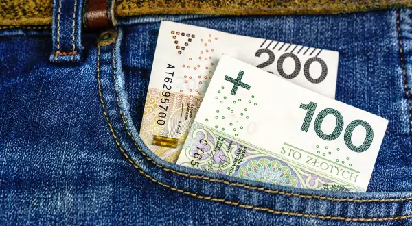 Polskie banknoty 100 i 200 zł w kieszeni dżinsów.