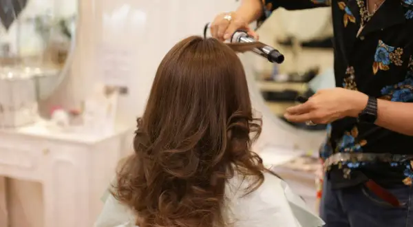 Styling włosów w domu: lokówka tworzy piękne fale na brązowych włosach.