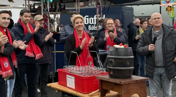 Menschen mit roten Schals klatschen bei Ruppichteroth Veranstaltungen. Eine Frau mit blonden Haaren steht im Mittelpunkt, daneben ein Mann mit Mikrofon.