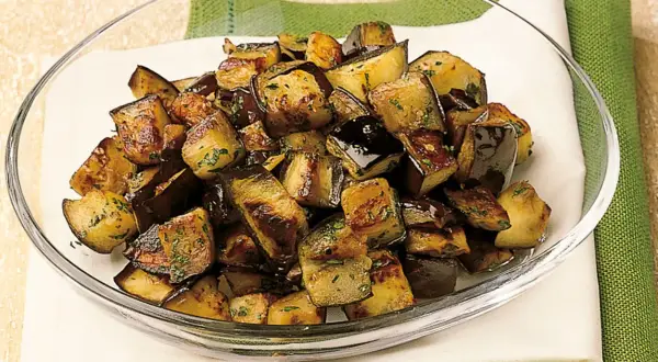 Melanzane a funghetto ricetta della nonna: cubetti dorati e saporiti, conditi con erbe aromatiche, pronti per essere gustati.