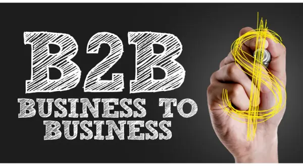 Mano disegna simbolo dollaro su lavagna con scritta "B2B Business to Business", il significato di B2B nel mondo degli affari.