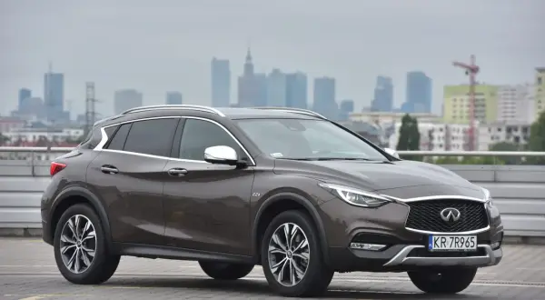 Brązowy Infiniti QX30 na tle miejskiej panoramy. Elegancki crossover gotowy na miejskie wyzwania.