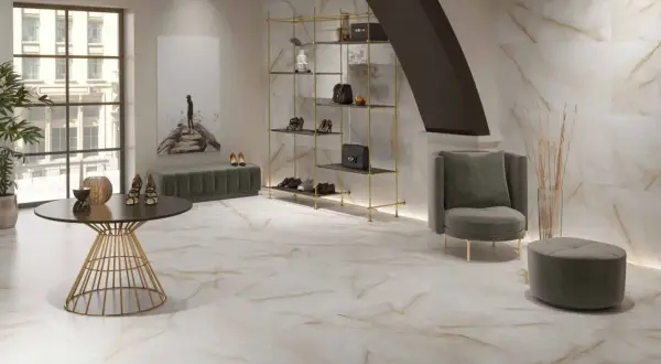 Elegantes suelos pintados con pintura imitan mármol veteado, complementando un salón moderno con estanterías doradas y mobiliario de terciopelo.