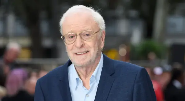 Uśmiechnięty Michael Caine w okularach, ikona kina. Jego niezapomniane role w licznych filmach na zawsze zapisały się w historii.