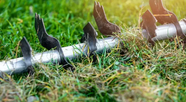 Metalowe ostrza aeratora w trawie, przygotowujące podłoże do lepszego wchłaniania składników odżywczych, kluczowych dla prawidłowej fertygacji.