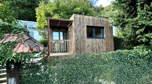 Une charmante tiny house en bois, nichée dans un jardin verdoyant, évoque un coin de nature paisible près de Paris.