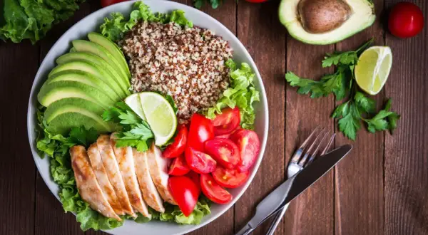 Schüssel mit Quinoa, Hähnchenbrust, Avocado, Tomaten und Salat. Ein leicht verdauliches Essen, das gut aussieht und schmeckt.
