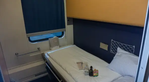 Gemütliches Bett im Nachtzug Berlin Wien. Kleine Flaschen und eine Tüte liegen bereit.