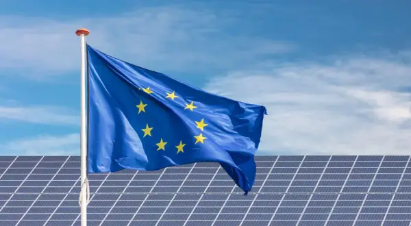 Bandera de la UE ondeando sobre placas solares en Extremadura, símbolo de ayudas para la energía limpia.