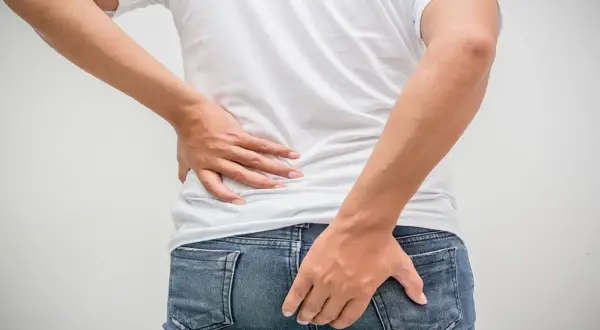 Mann hält sich den Rücken und das Gesäß. Möglicher tumor am after.