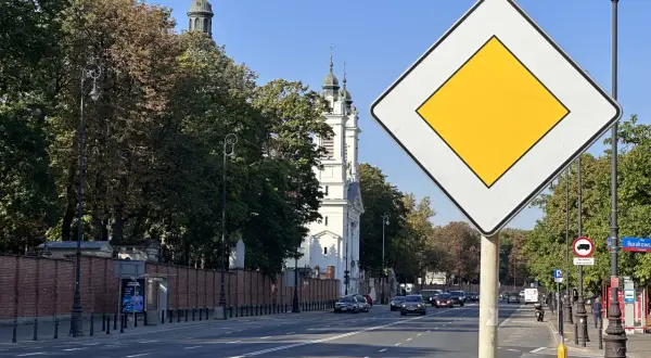 Znak "koniec drogi z pierwszeństwem" na tle kościoła i drzew. Ulica Burakowska w Warszawie.