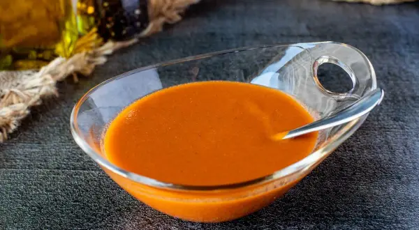 Un cuenco de cristal con una deliciosa salsa americana anaranjada, lista para acompañar tus platos.