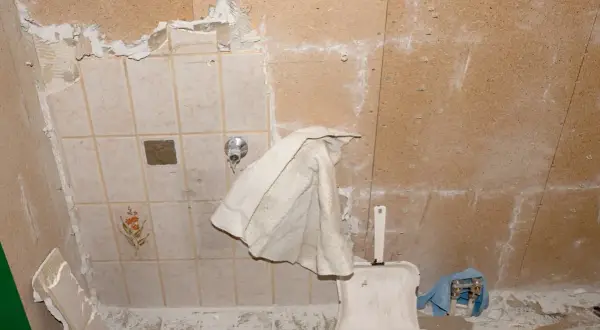 Renovierungsarbeiten: alte Fliesen werden entfernt, um Platz für neue zu schaffen. Staub und Schutt bedecken den Boden.