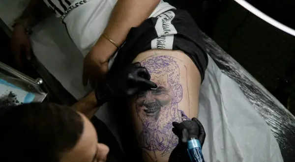Un tatuador trabaja en un retrato en la pierna de un cliente, demostrando la habilidad de los mejores tatuadores de España.
