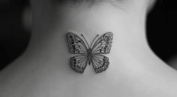Delikatny czarny motyl tatuaż na karku. Czarny motyl znaczenie: przemiana, wolność, nadzieja.