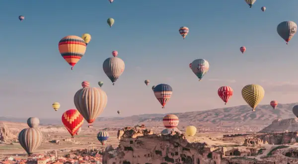 Många färgglada luftballonger svävar över Cappadocias unika landskap i Turkiet. En magisk luftballong turkiet-upplevelse.