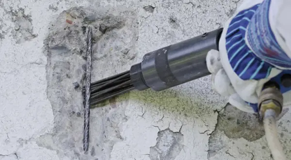 Narzędzie pneumatyczne przygotowuje beton do naprawy na zewnątrz.
