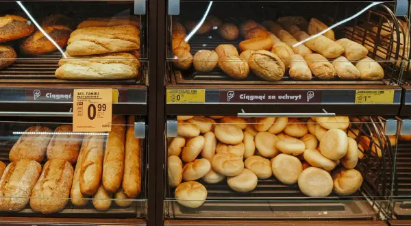 Na półkach sklepowych widać świeże pieczywo: bagietki, bułki i chlebki. Obok znajduje się etykieta z napisem "Biedronka", sugerująca, że to bułka o niskim IG, idealna dla dbających o linię.