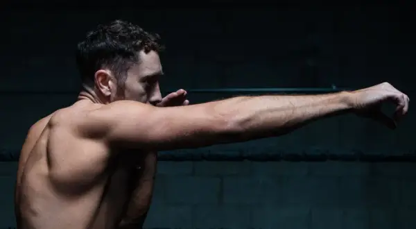 A boxer throws a powerful right jab, his muscles tensed and ready.
