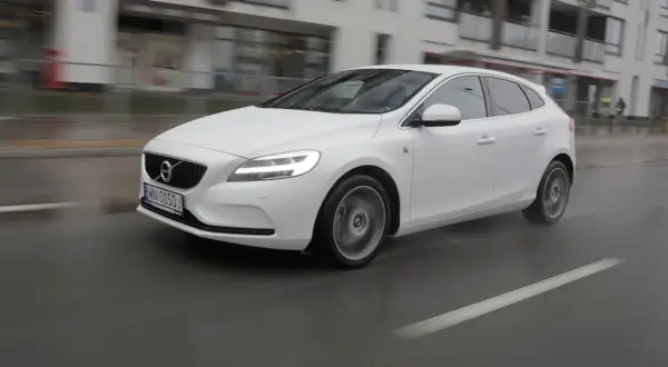 Białe Volvo V40 D3 w ruchu miejskim, na mokrej nawierzchni.