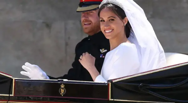 Meghan Markle y el Príncipe Harry sonríen en su carruaje nupcial. La novia luce un velo y tiara deslumbrantes en su boda.