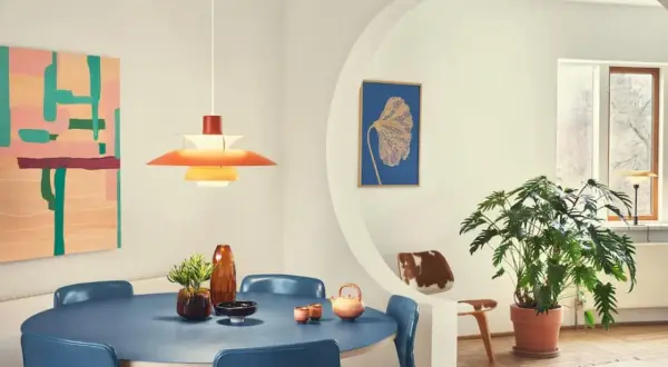 Ein Esszimmer im **mid century modern** Stil mit blauem Tisch, blauen Stühlen, einer bunten Wandkunst und einer markanten Hängeleuchte.