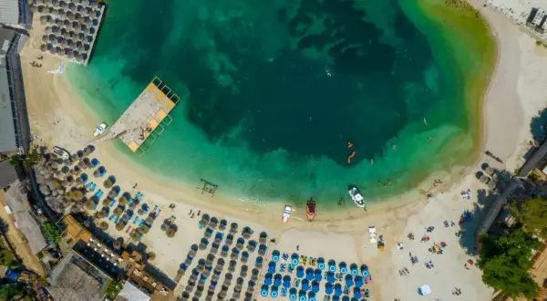 Albania, styczeń: plaża z leżakami i parasolami, turkusowa woda, łodzie. Pogoda idealna na relaks.