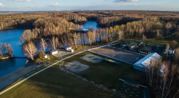 Malownicze **Czechowice jezioro** otoczone lasem, z widokiem na stadninę koni i zabudowania.