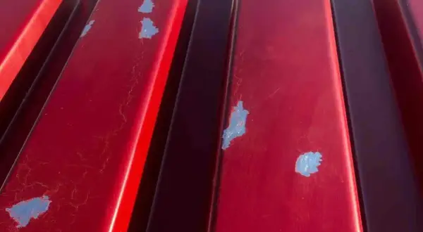 Detalles de la chapa galvanizada roja con pintura descascarada, mostrando el proceso de pintar chapa galvanizada.