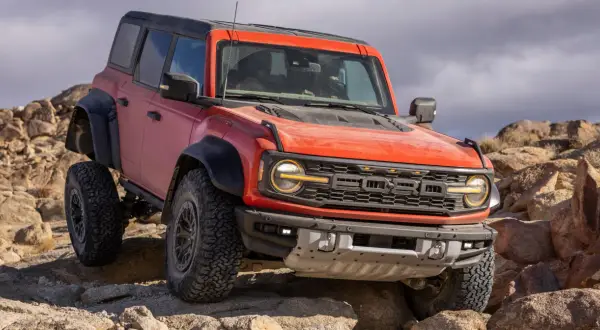 Pomarańczowy Ford Bronco Raptor pokonuje skalisty teren, demonstrując swoją terenową moc.
