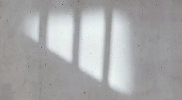 Cień strumienicy na betonowej ścianie. Gra światła i cienia tworzy abstrakcyjny wzór.