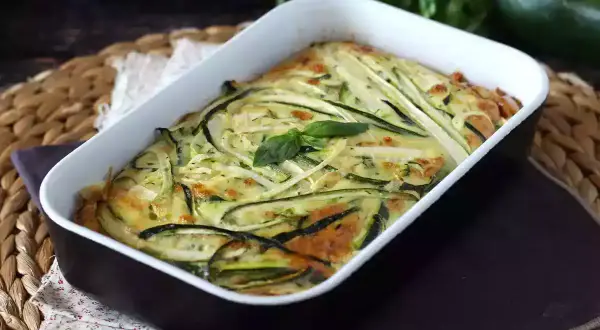 En gyllene frittata i ugn med tunna skivor zucchini och färska örter. En härlig rätt som doftar sommar.
