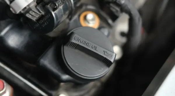Czarna zakrętka silnika z napisem "ENGINE OIL" i ikonką miarki oleju.
