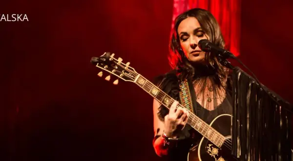 Kasia Kowalska na scenie, grając na gitarze i śpiewając. Jej utwory poruszają serca publiczności.