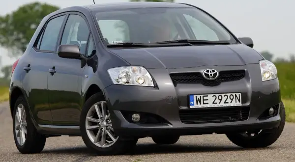 Szary Toyota Auris z przodu. Widać dwa światła cofania, jedno po każdej stronie zderzaka.