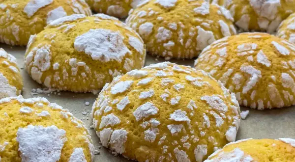 Popękane ciasteczka cytrynowe, posypane cukrem pudrem, wyglądają jak małe, słodkie śnieżki.