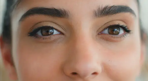 Brązowe oczy z subtelnym makijażem podkreślającym ich kształt, tworzącym efekt rzęsy foxy eyes.